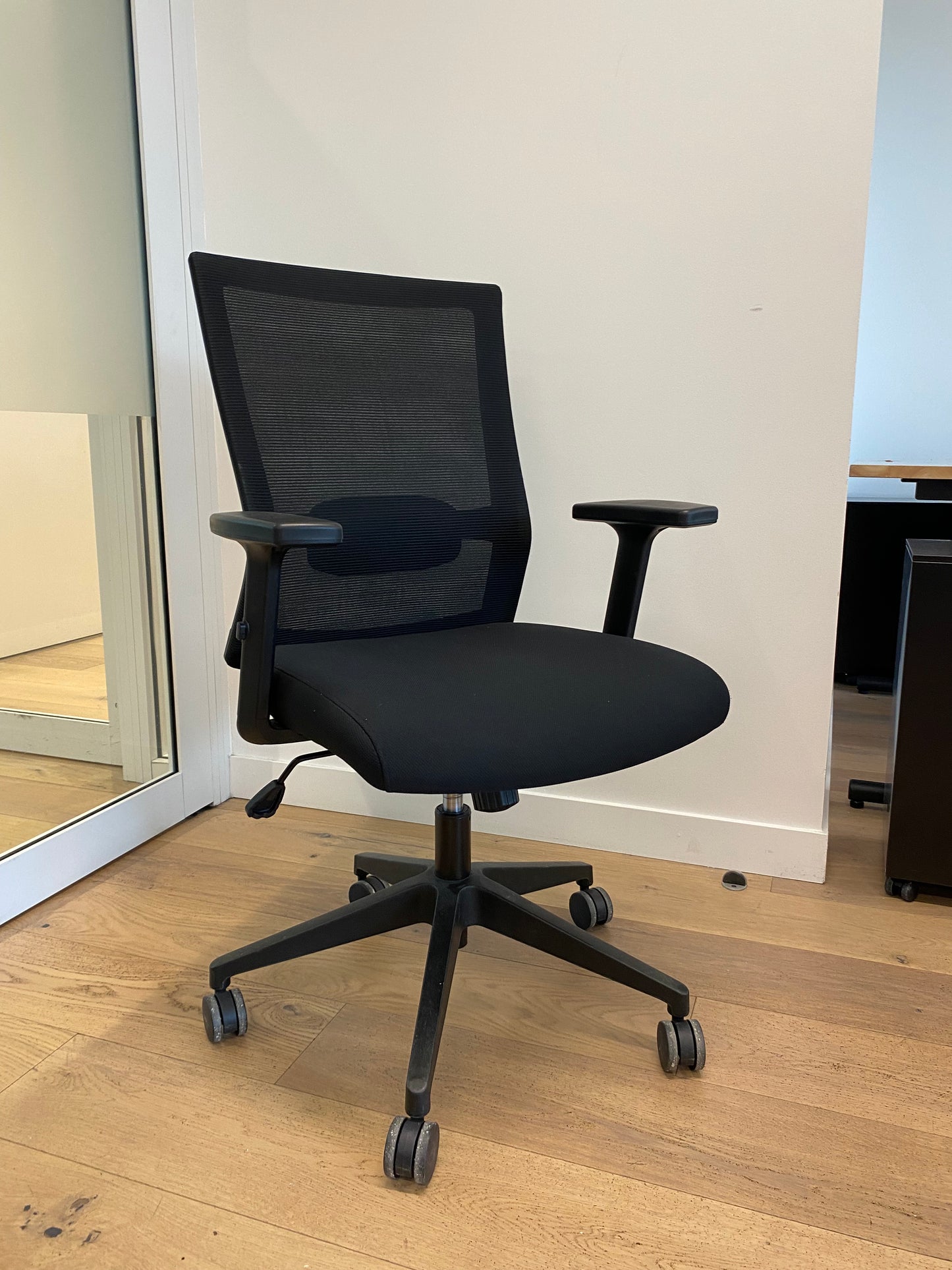 Fauteuil de bureau reconditionné noir avec dossier en maille et roulettes pivotantes.