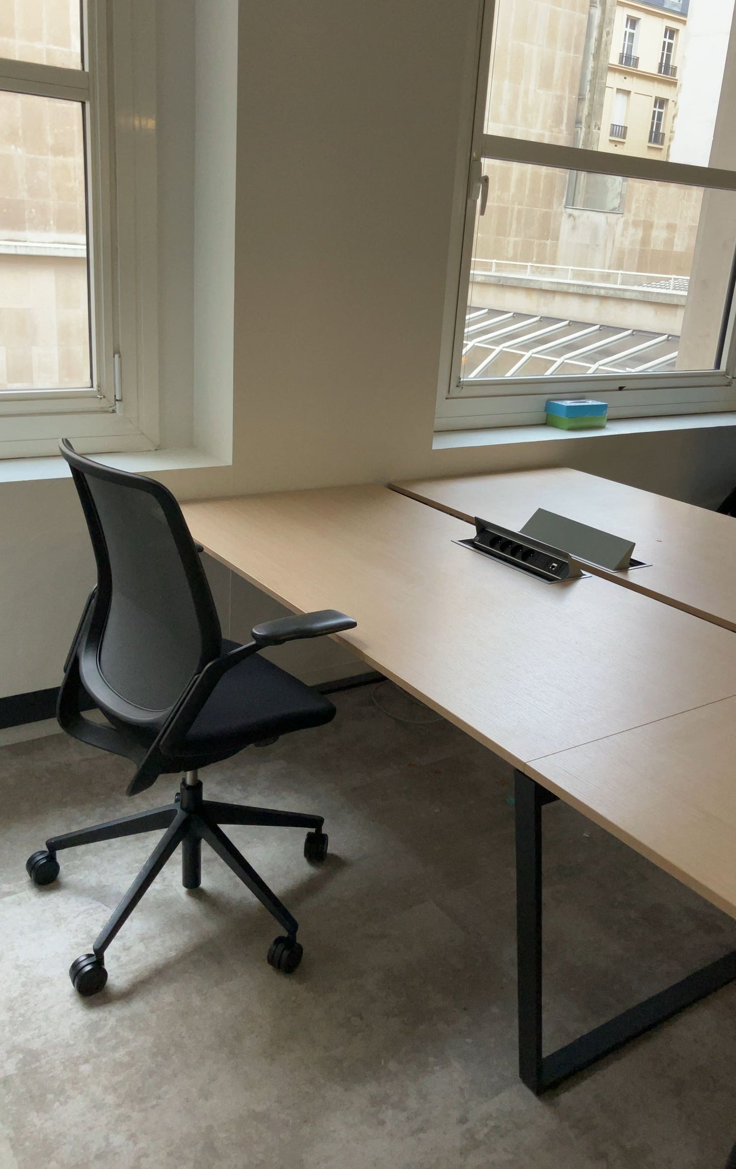 Bureau bench d'occasion en bois clair avec fauteuil ergonomique noir.