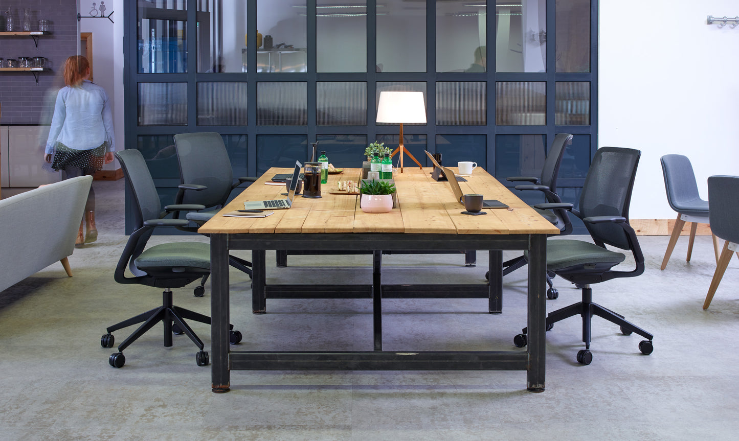 Espace de coworking avec table en bois, chaises ergonomiques et accessoires.