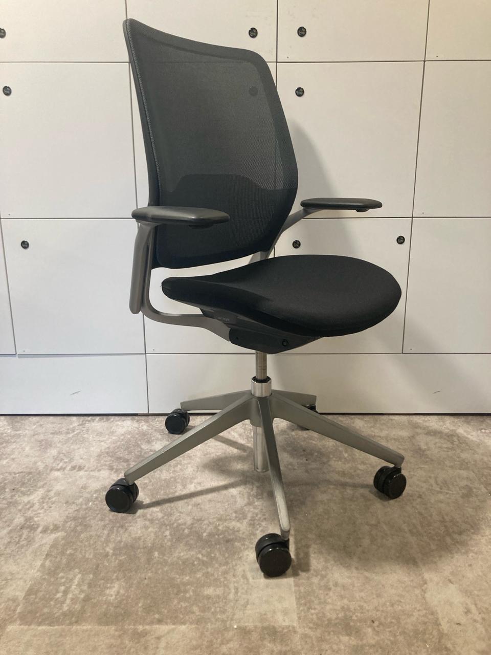 Chaise de bureau reconditionnée noire avec piètement métallique et dossier en maille.