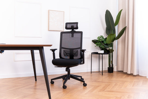 Fauteuil de bureau ergonomique reconditionné à dossier résille et appuie-tête, près d'un bureau en bois