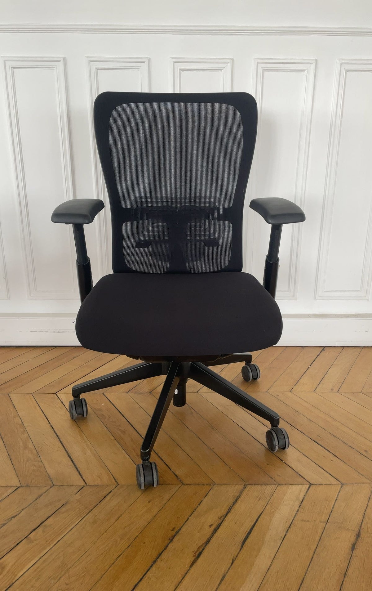 Chaise de bureau reconditionnée avec dossier en maille noire et assise rembourrée.