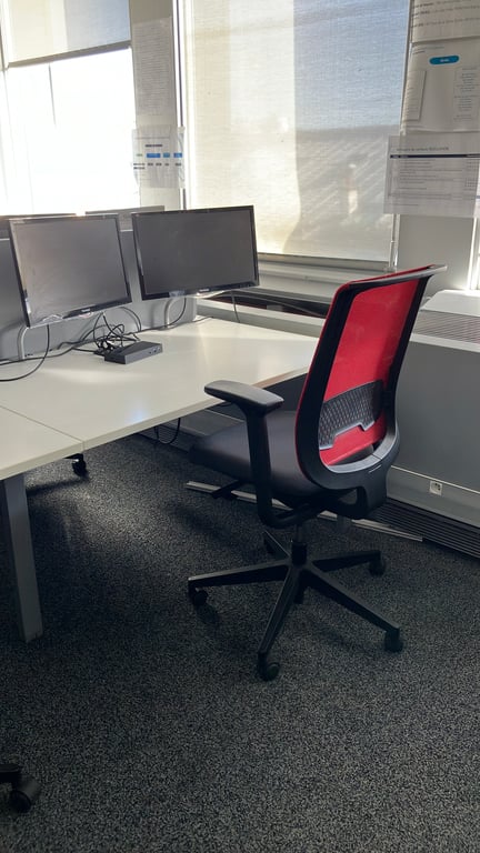 Fauteuil de bureau avec dossier en résille rouge et assise en tissu noir sur piètement en étoile